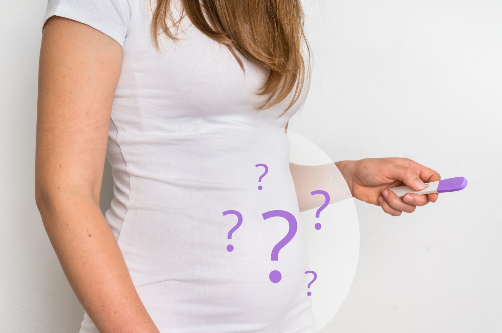 mujer sosteniendo una prueba de embarazo con signos de interrogación