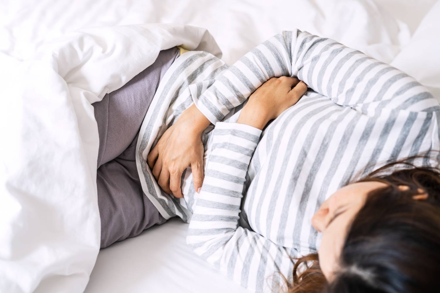 Mujer joven con dolor de estómago en la cama
