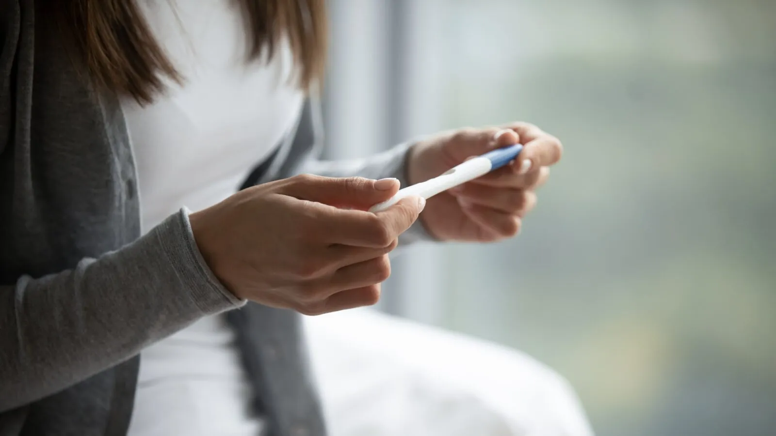 woman holding a pregnancy test to read it