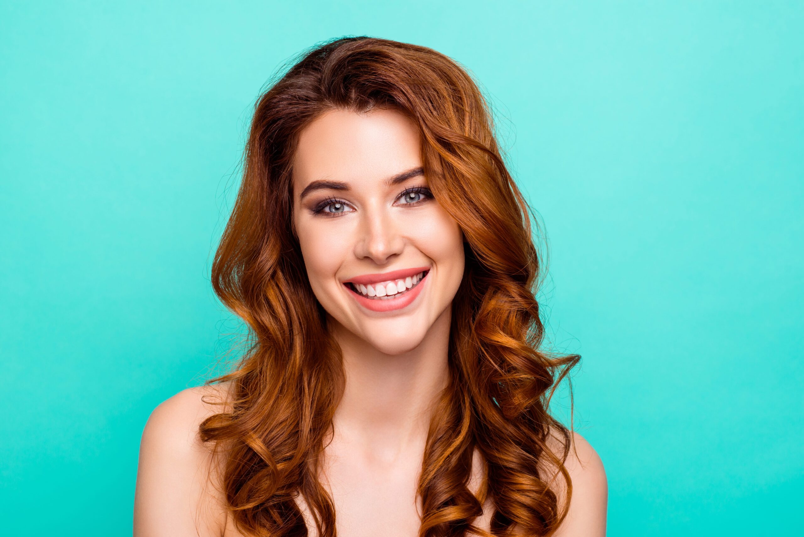 redhead smiling against teal background